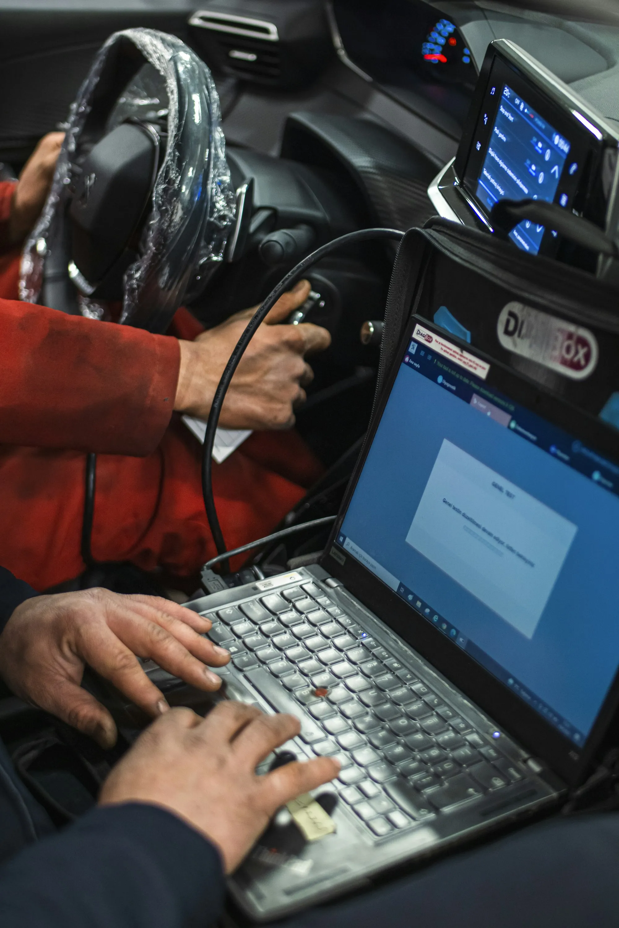 Laptop showing diagnostic software on a vehicle's front seat