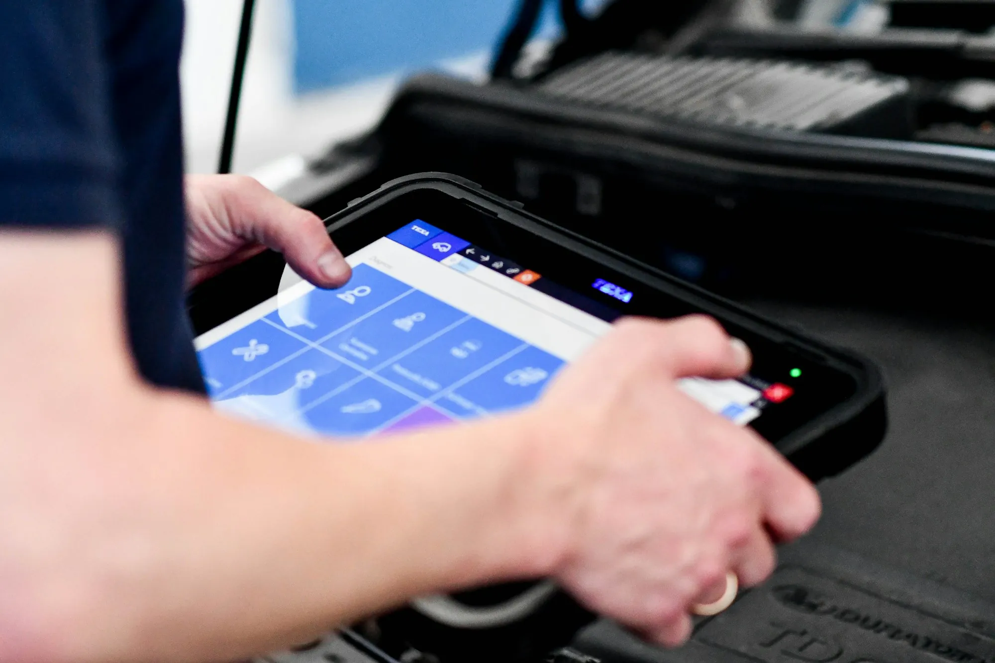 Technician using a handheld scan tablet connected to a car