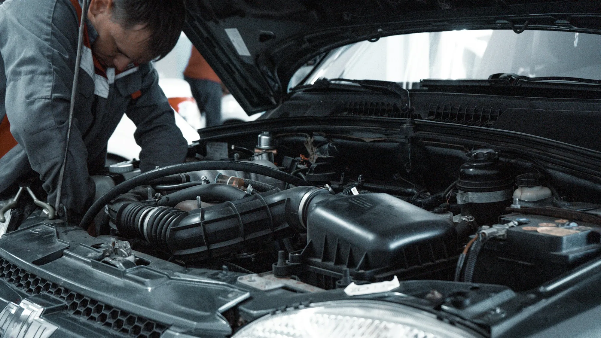 Mechanic with tools working inside an open engine bay