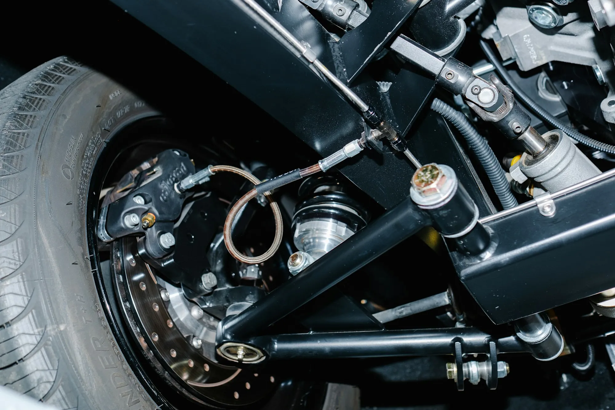 Front suspension, brake disc and control arm visible beneath a lifted car
